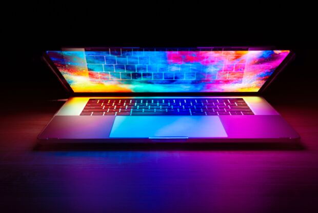 Ein Laptop, halb geöffnet, strahlt bunte Farben aus dem Display